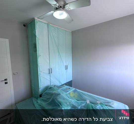 חדר עם רהיטים מכוסים בניילון לקראת צביעה